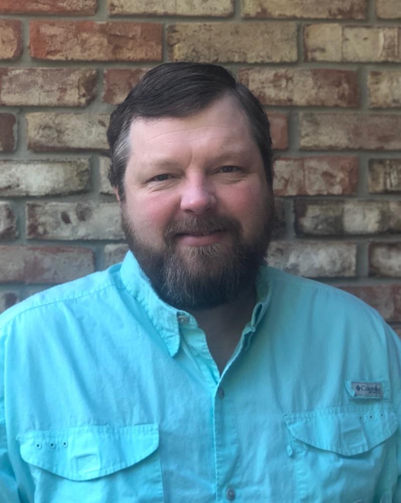 man with beard and blue shirt smiling at camera